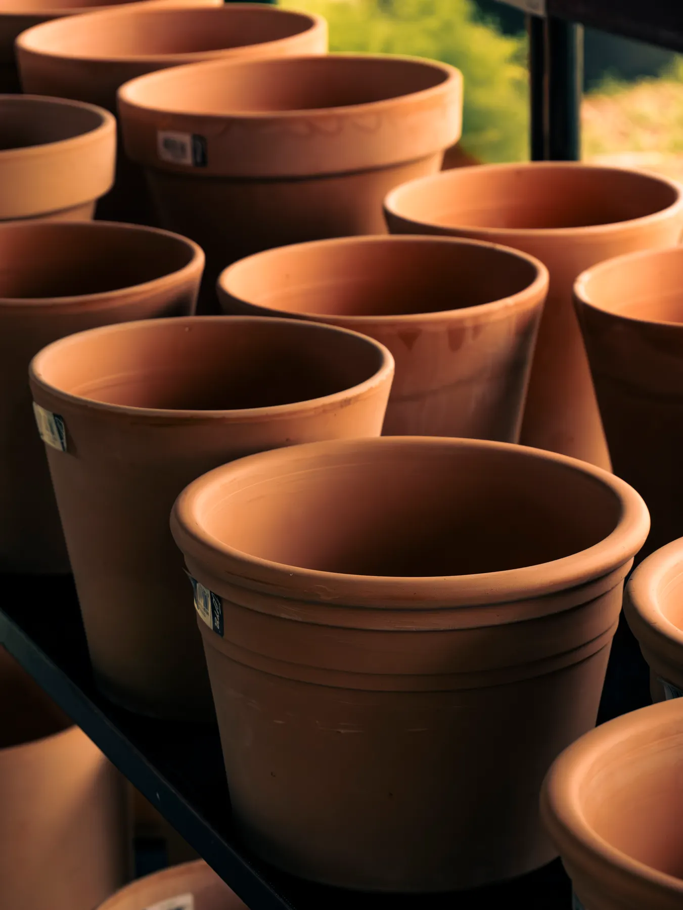 Macetas de barro apiladas junto a plantas