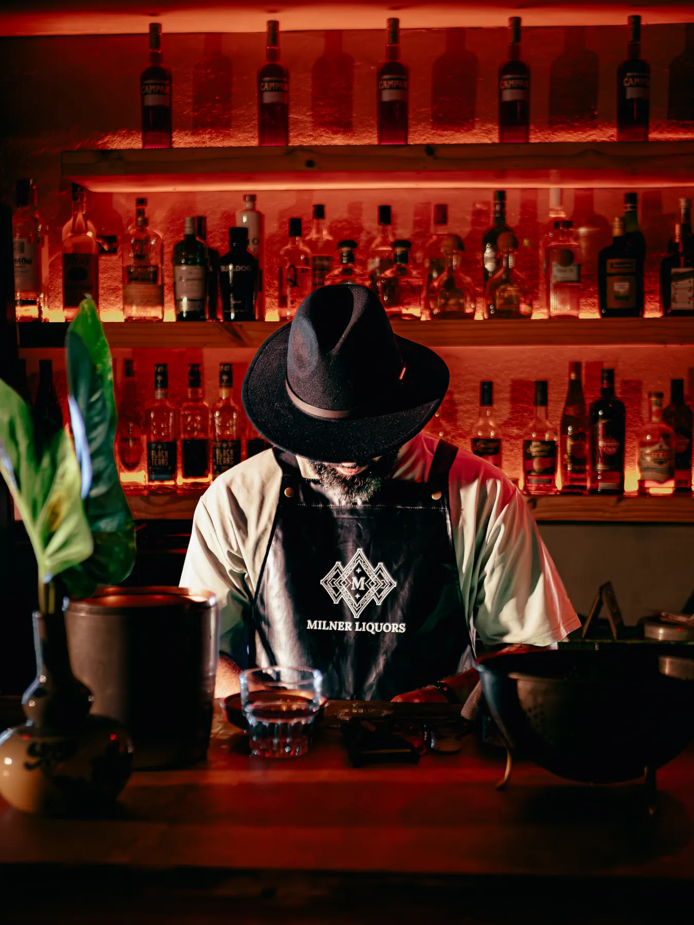 Bartender con sombrero preparando tragos frente a la botillería