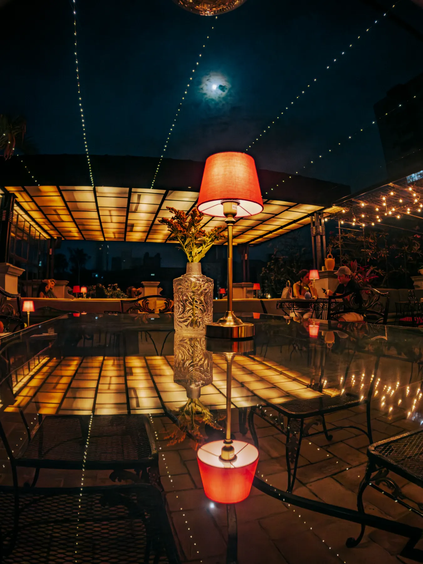 Lámpara roja sobre una mesa de la terraza de noche